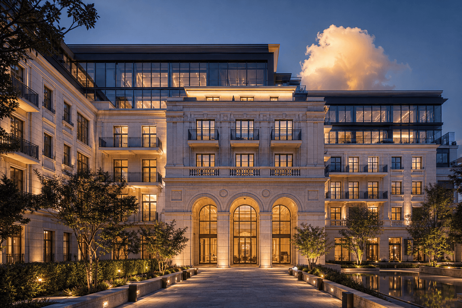 Luxus-Hotel und Serviced Apartments in Wien — beleuchtete Steinfassade mit Brunnen im Vorhof bei Abenddämmerung